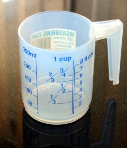 A simple plastic measuring cup capable of holding the volume one cup. প্লাস্টিকের পরিমাপ কাপ, এক কাপ পরিমান [ A simple plastic measuring cup, capable of holding the volume one cup. ]